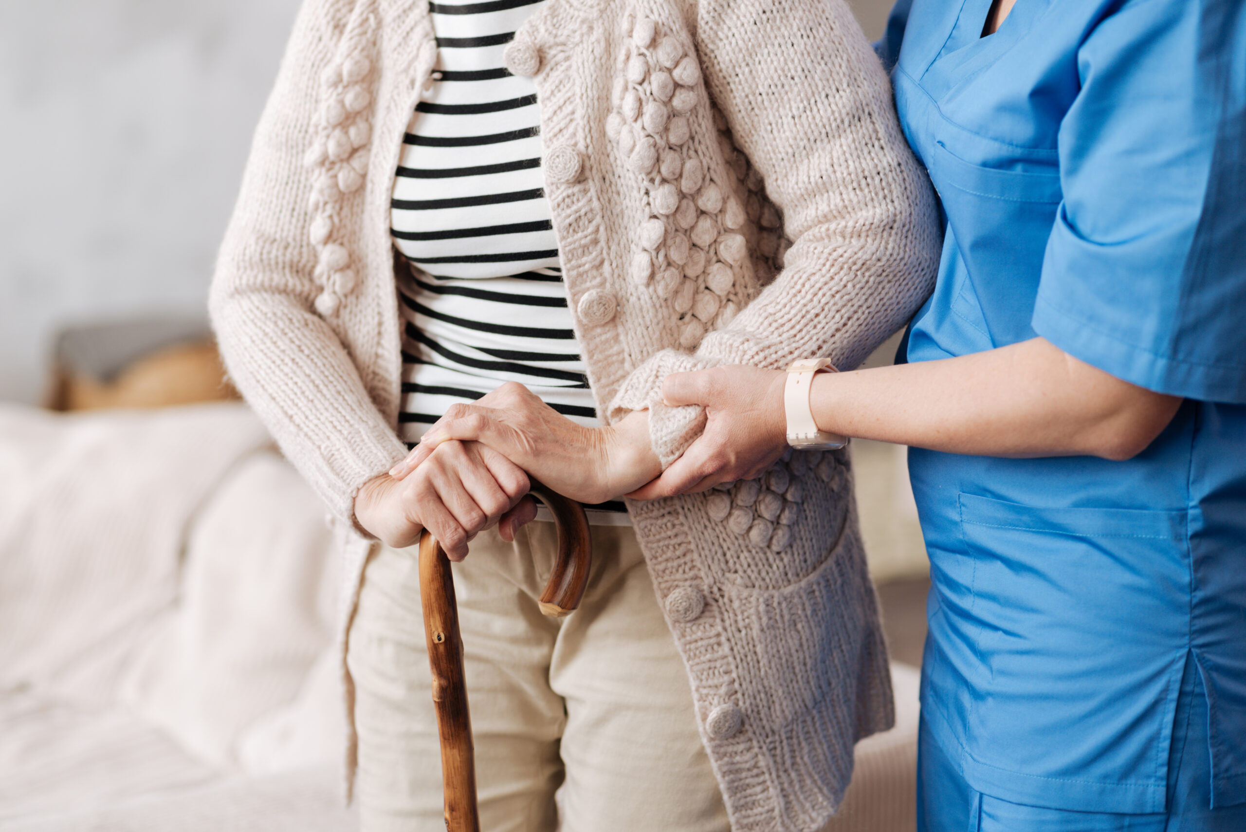 Caregiver helping an elderly woman walk with a cane