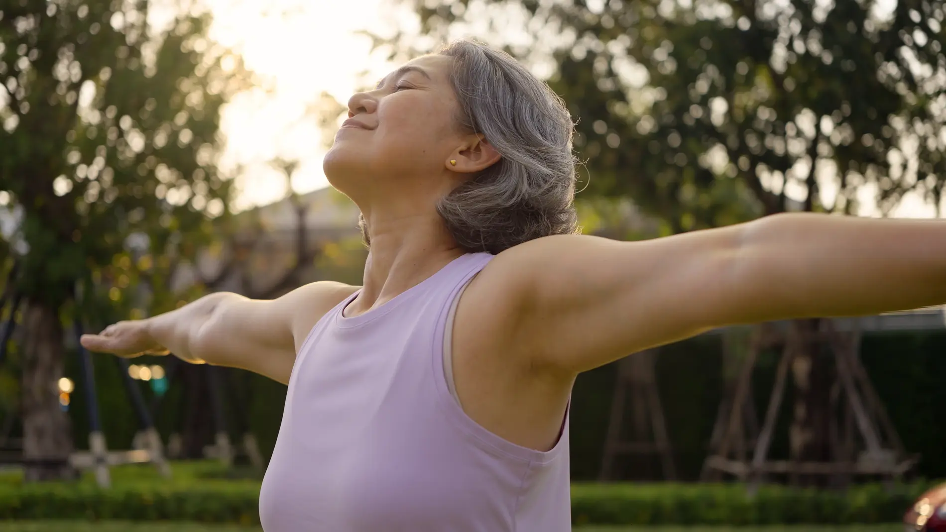 Woman enjoying outdoor relaxation with open arms at park.